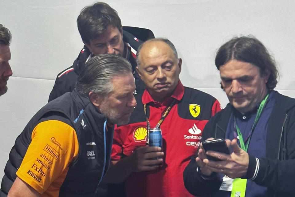 A reporter shows McLaren CEO Zak Brown, lower left, Mercedes team principal Toto Wolff, top left, and Ferrari team principal Frédéric Vasseur a video following the shortened first practice session for the Formula One Las Vegas Grand Prix auto race, Thursday, Nov. 16, 2023, in Las Vegas. (AP Photo/Jenna Fryer)