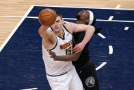 Denver Nuggets' Nikola Jokic (15) and Minnesota Timberwolves' Naz Reid collide during the first half of an NBA basketball game Thursday, May 13, 2021, in Minneapolis. (AP Photo/Jim Mone)