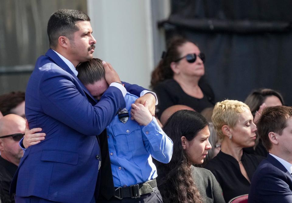 Family member Raphael Rodriguez hugs an officer during Jorge Pastore's funeral service Friday at Circuit of the Americas.