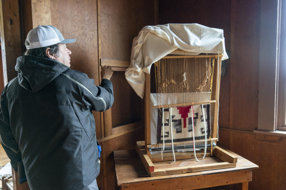 Dr. Leslie Hannah uncovers a loom in the Ataloa Lodge Museum at Bacone College, on Jan. 8 2024, in Muskogee, Okla. Founded in 1880 as a Baptist missionary college focused on assimilation, Bacone College transformed into an Indigenous-led institution that provided an intertribal community, as well as a degree. (AP Photo/Nick Oxford)