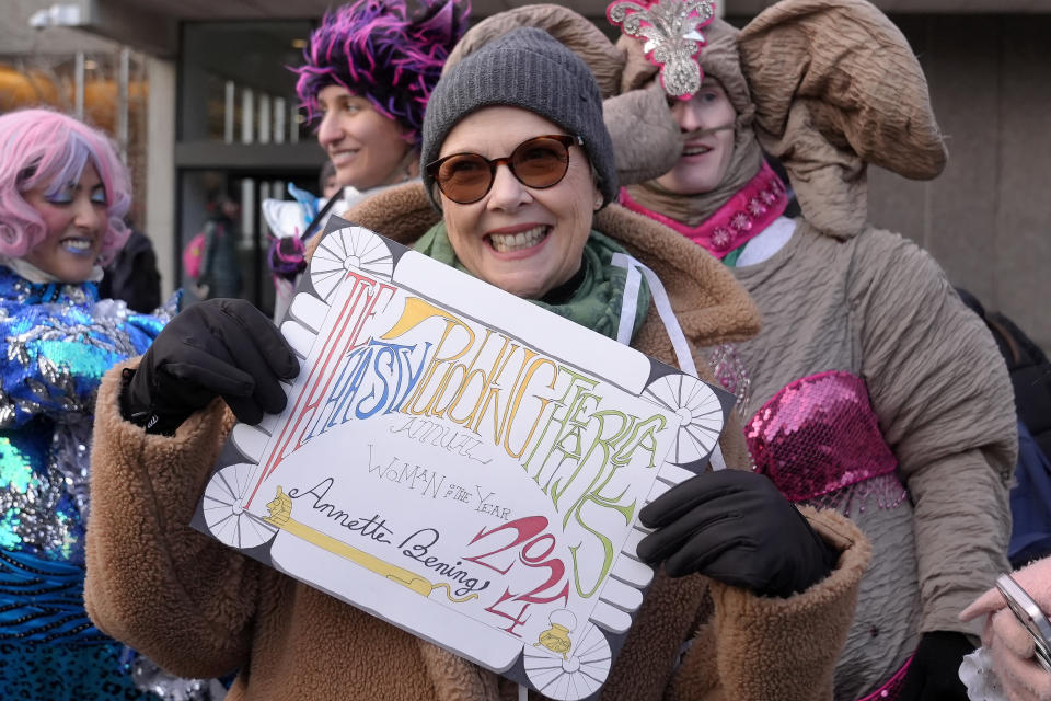 Actor Annette Bening, center, Hasty Pudding 2024 Woman of the Year, displays an award placard following a parade, Tuesday, Feb. 6, 2024, through Harvard Yard, on the campus of Harvard University, in Cambridge, Mass. The award was presented to Bening by Hasty Pudding Theatricals, a theatrical student society at Harvard. (AP Photo/Steven Senne)