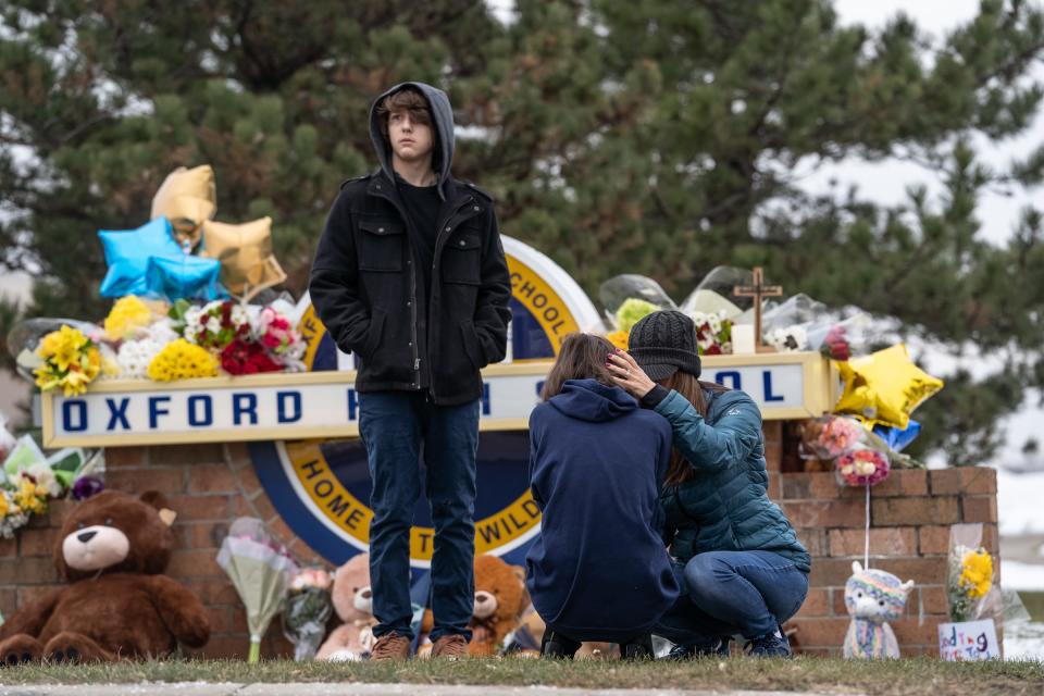 People comfort each other while visiting a memorial being built at an entrance to Oxford High School on December 1, 2021, following an active shooter situation at Oxford High School that left four students dead and multiple others with injuries.