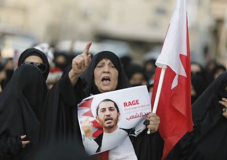 A woman shouts anti-government slogans as she holds a placard with an image of Al Wefaq Secretary-General Sheikh Ali Salman during a demonstration for him in the village of Bilad Al Qadeem, south of Manama, December 29, 2014. REUTERS/Hamad I Mohammed