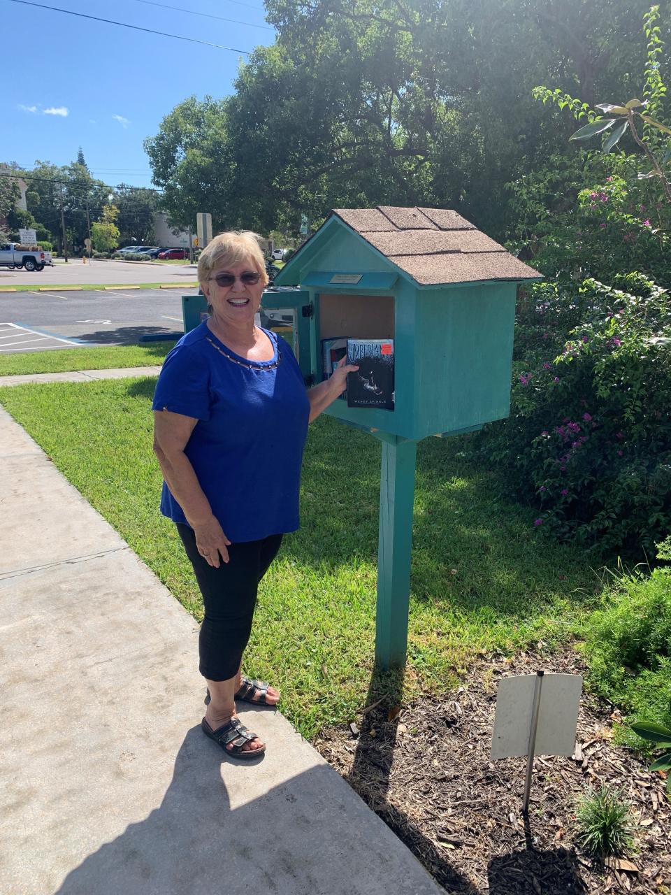 Suzanne Bennitt, president of the Community Woman's Club, shows off the organization's Little Library, on the grounds of Magnolia Hall in Cocoa Village.