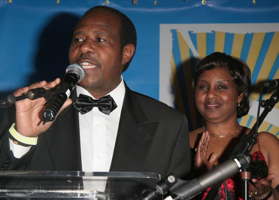 Paul Rusesabagina speaking into a microphone next to his wife