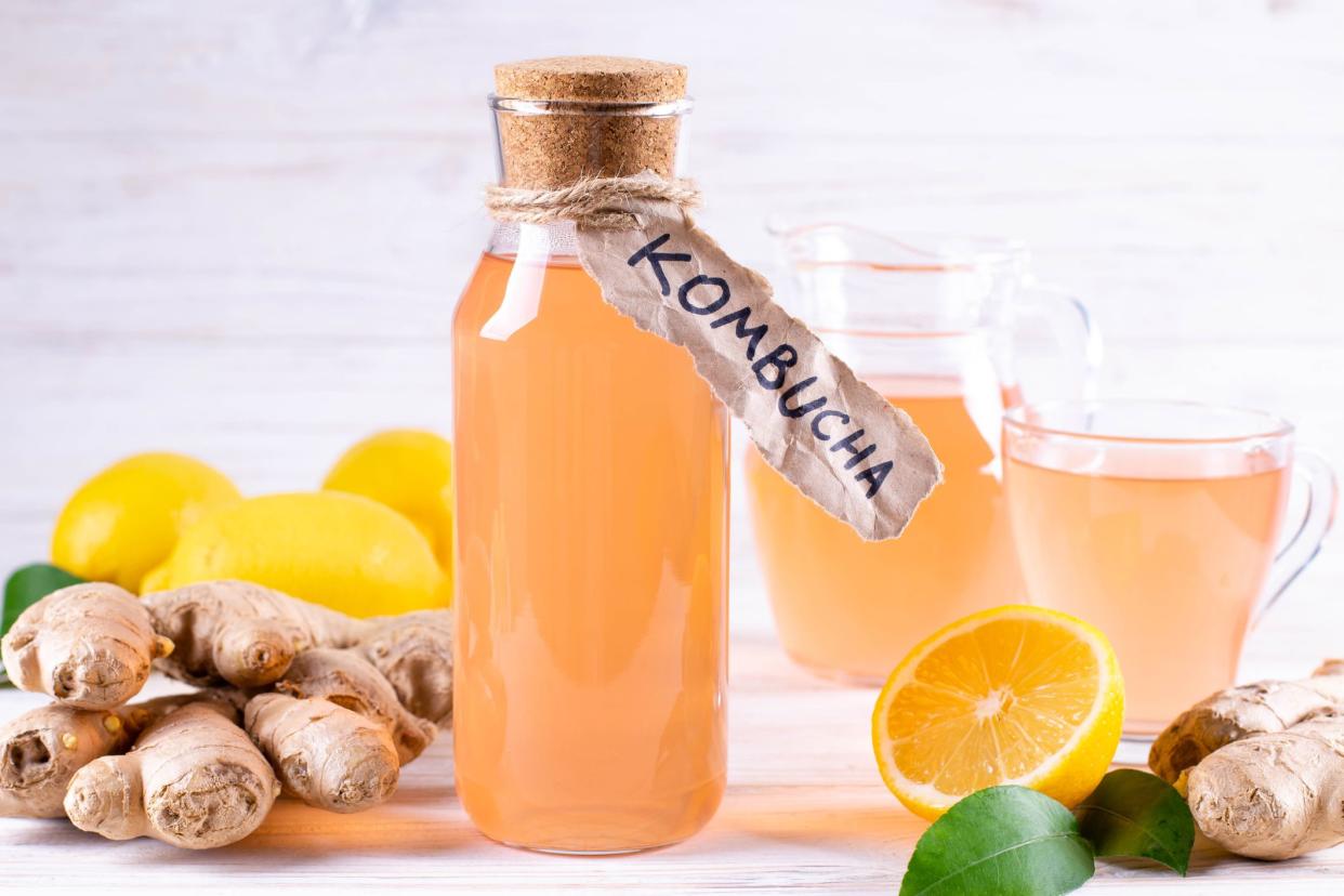 Refreshing filtered kombucha tea in a glass bottle and glass, with label written kombucha on white wooden background.