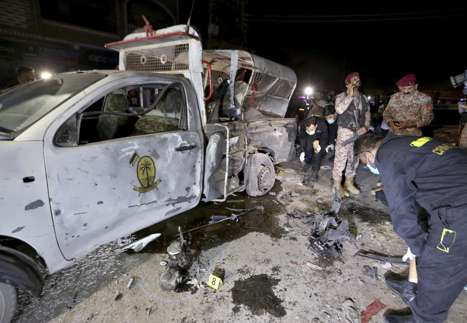 Pakistani security officials examine the site of explosion, in Karachi, Pakistan, Monday, March 15, 2021. The roadside bomb went off near a vehicle carrying paramilitary rangers in southern Pakistan on Monday, killing and wounding some people, mostly pedestrians, authorities said. (AP Photo/Fareed Khan)
