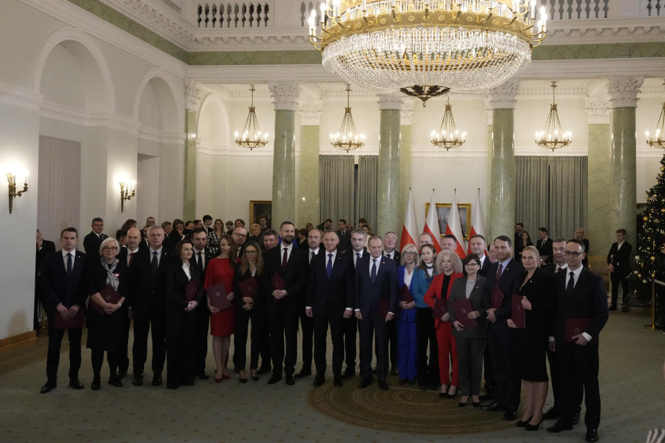 Poland's new Prime Minister Donald Tusk and Poland's President Andrzej Duda, centre, pose with cabinet members after the swearing-in ceremony at the presidential palace in Warsaw, Poland, Wednesday, Dec. 13, 2023. Donald Tusk was sworn in by the president in a ceremony where each of his ministers was also taking the oath of office. (AP Photo/Czarek Sokolowski)