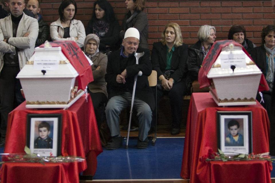 An ethnic Albanian man mourns near 27 coffins draped with Albanian flags containing the remains of ethnic Albanians killed during the 1998-99 Kosovo war in the town of Suva Reka during the funeral ceremony on Wednesday, March 26, 2014. The victims were killed in two separate rampages by Serbs forces in town of Suva Reka and Mala Krusa just days after NATO began a bombing campaign to end an onslaught by Serbia on separatist ethnic Albanians. (AP Photo/Visar Kryeziu)