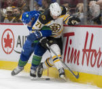 Vancouver Canucks center J.T. Miller (9) fights for control of the puck with Boston Bruins left wing Taylor Hall (71) during the first period of an NHL hockey game Wednesday, Dec. 8, 2021 in Vancouver, British, Columbia. (Jonathan Hayward/The Canadian Press via AP)