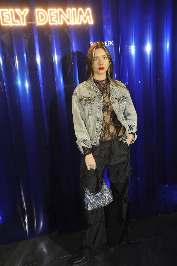 Lucía Celasco deslumbró con un look que combinó varios estilos. La joven eligió un body transparente, un pantalón deportivo y una campera de jean bordada, uno de los clásicos de su marca. El toque glam se lo aportó con una cartera de glitter plateada