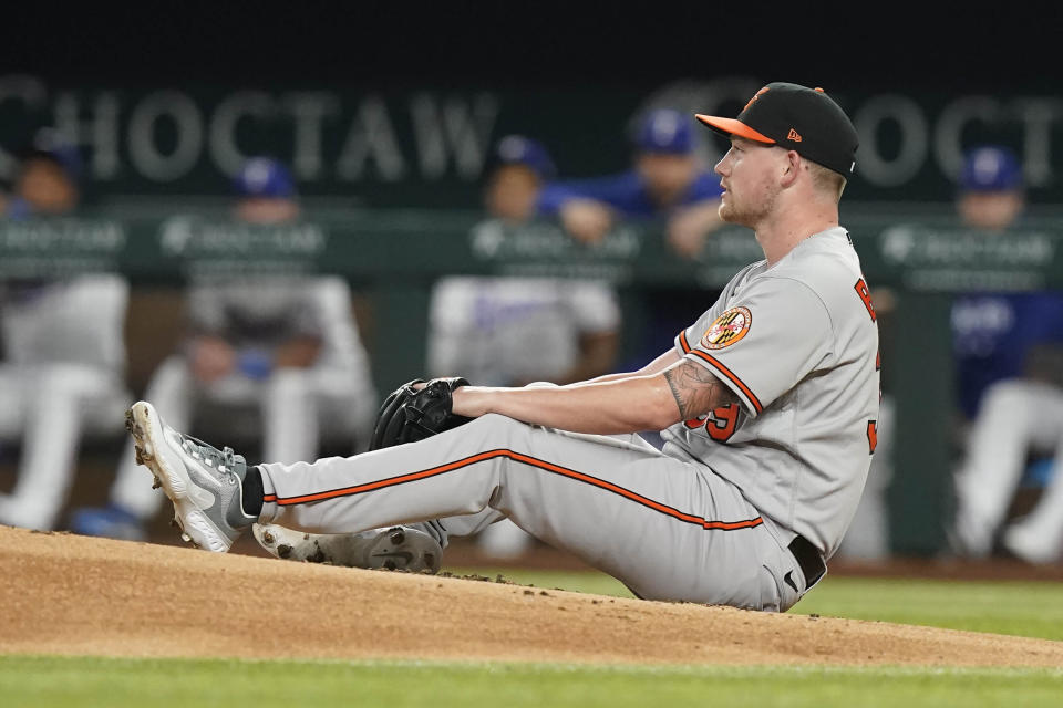 Baltimore Orioles starting pitcher Kyle Bradish sits on the mound after his foot was hit during the second inning of a baseball game against the Texas Rangers in Arlington, Texas, Monday, April 3, 2023. Bradish left the game. (AP Photo/LM Otero)