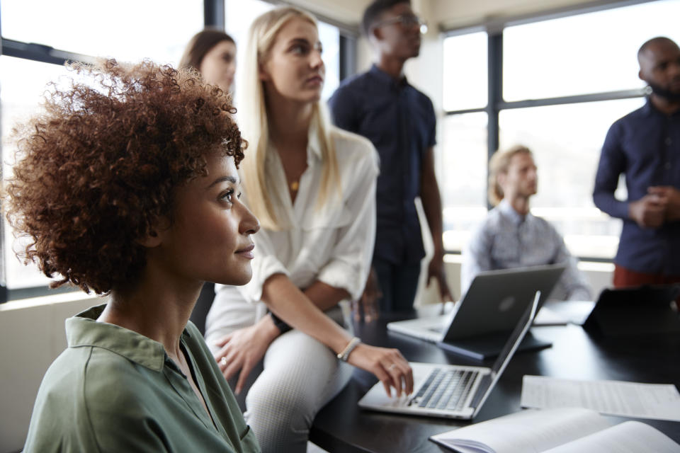 Close up of creative business colleagues listening to an informal presentation in a meeting room