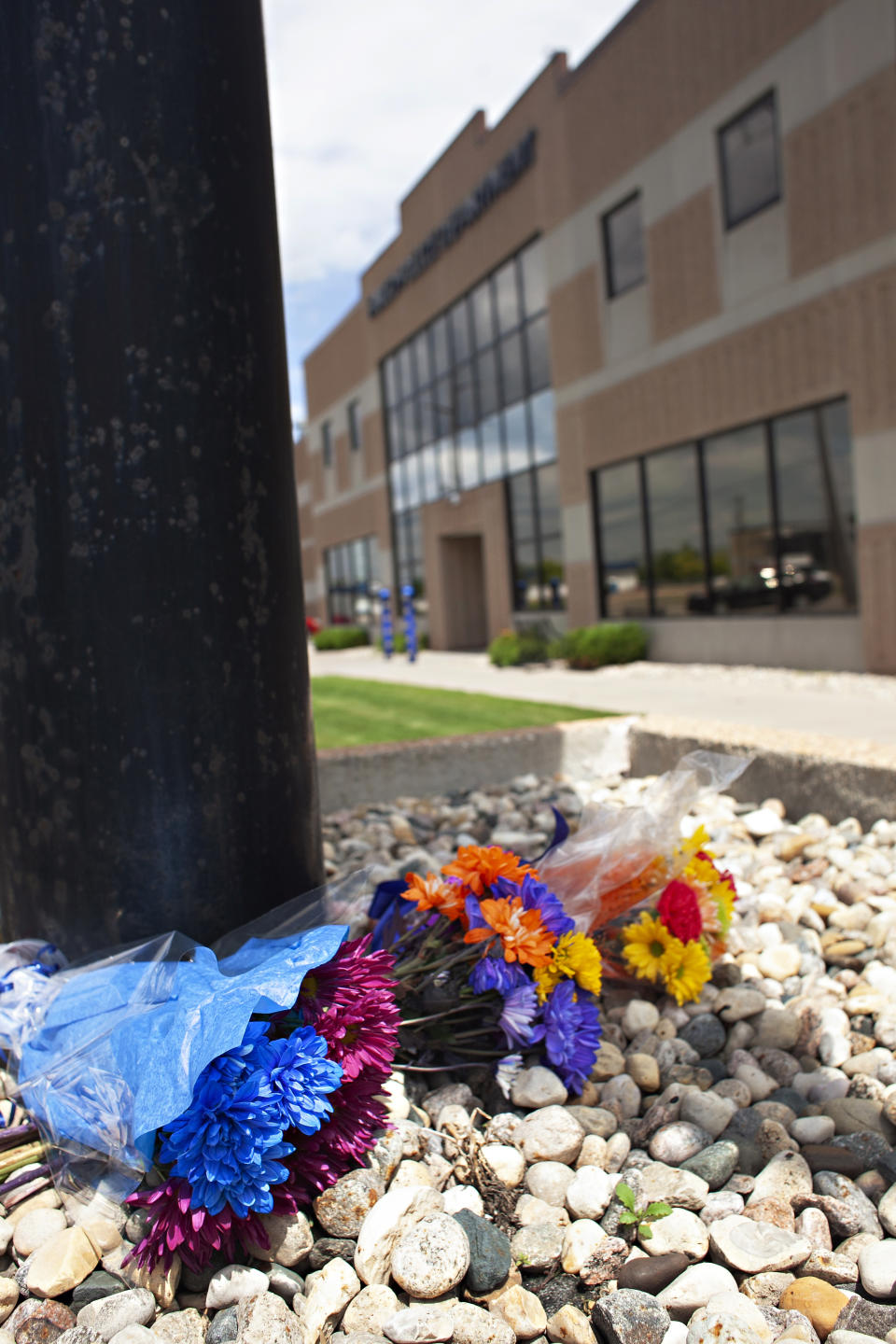 Several flower bouquets lie outside the Fargo Police Department, Saturday, July 15, 2023, in Fargo, N.D. One police officer was fatally shot and two others were critically wounded a day earlier. Authorities have said the suspect was also killed in the shooting, and a civilian was injured. (AP Photo/Ann Arbor Miller)