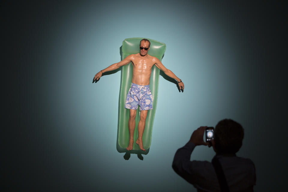 A visitor photographs a sculpture entitled 'Drift' by Australian artist Ron Mueck during the opening day of his exhibition at the Museum of Modern Art in Rio de Janeiro, Brazil, Wednesday, March 19, 2014. The exhibition will run from today to June 1, 2014. (AP Photo/Felipe Dana)