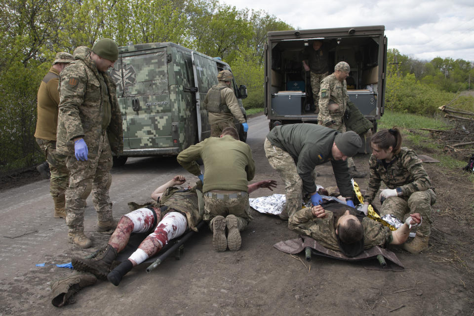 FILE - Military medics give first aid to wounded soldiers on the road near Bakhmut, Donetsk region, Ukraine, Thursday, May 11, 2023. Ukrainian President Volodymyr Zelenskyy said Sunday, May 21, 2023 that Russian forces weren't occupying Bakhmut, casting doubt on Moscow's insistence that the eastern Ukrainian city had fallen. The fog of war made it impossible to confirm the situation on the ground in the invasion’s longest battle, and the comments from Ukrainian and Russian officials added confusion to the matter. (AP Photo/Boghdan Kutiepov, File)