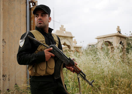 A Kurdish Peshmerga fighter stands in a cemetery in Tel Asqof, northern Iraq May 4, 2016. REUTERS/Goran Tomasevic