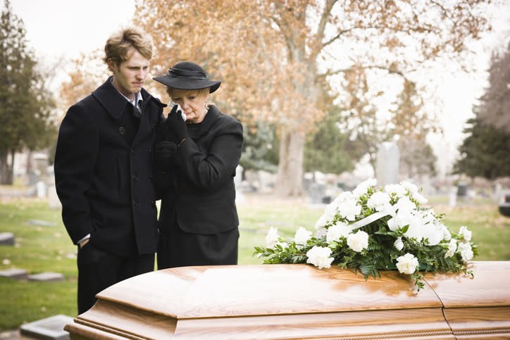 People standing beside a coffin