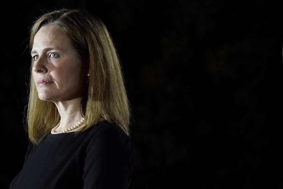 FILE - In this Oct. 26, 2020, file photo Amy Coney Barrett, listens as President Donald Trump speaks before Supreme Court Justice Clarence Thomas administers the Constitutional Oath to Barrett on the South Lawn of the White House in Washington, after she was confirmed by the Senate. Barrett is expected to join her new colleagues on the Supreme Court on Monday, Nov. 2, to hear arguments for the first time. (AP Photo/Patrick Semansky, File)