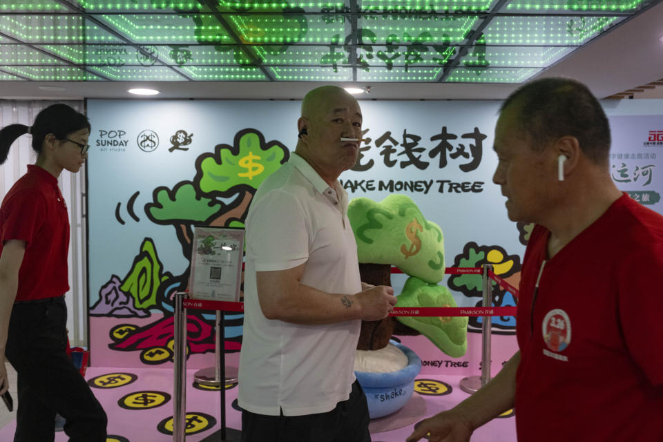 Visitors to a mall pass through a promotion section for shopping coupons in Beijing, Thursday, July 25, 2024. (AP Photo/Ng Han Guan)