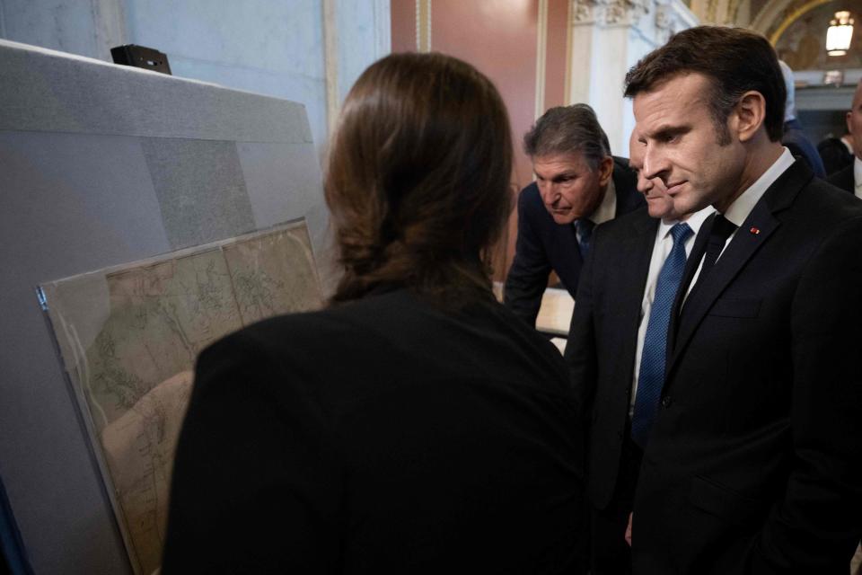 U.S. Sens. Joe Manchin, D-W.V, and Chris Coons, D-Del., show French President Emmanuel Macron documents of French relevance, prior to a working lunch on climate and biodiversity issues.