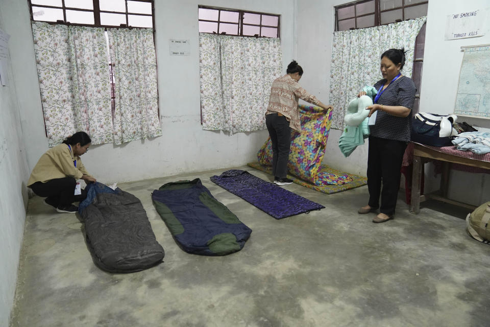 Polling officers, left to right, Neke W Konyak, 29, Dekule Kapfo, 34, and Nukutholu Nienu, 44, make their beds on a concrete floor, on the eve of polling in Chedema village, in the northeastern Indian state of Nagaland, Thursday, April 18, 2024. (AP Photo/Yirmiyan Arthur)