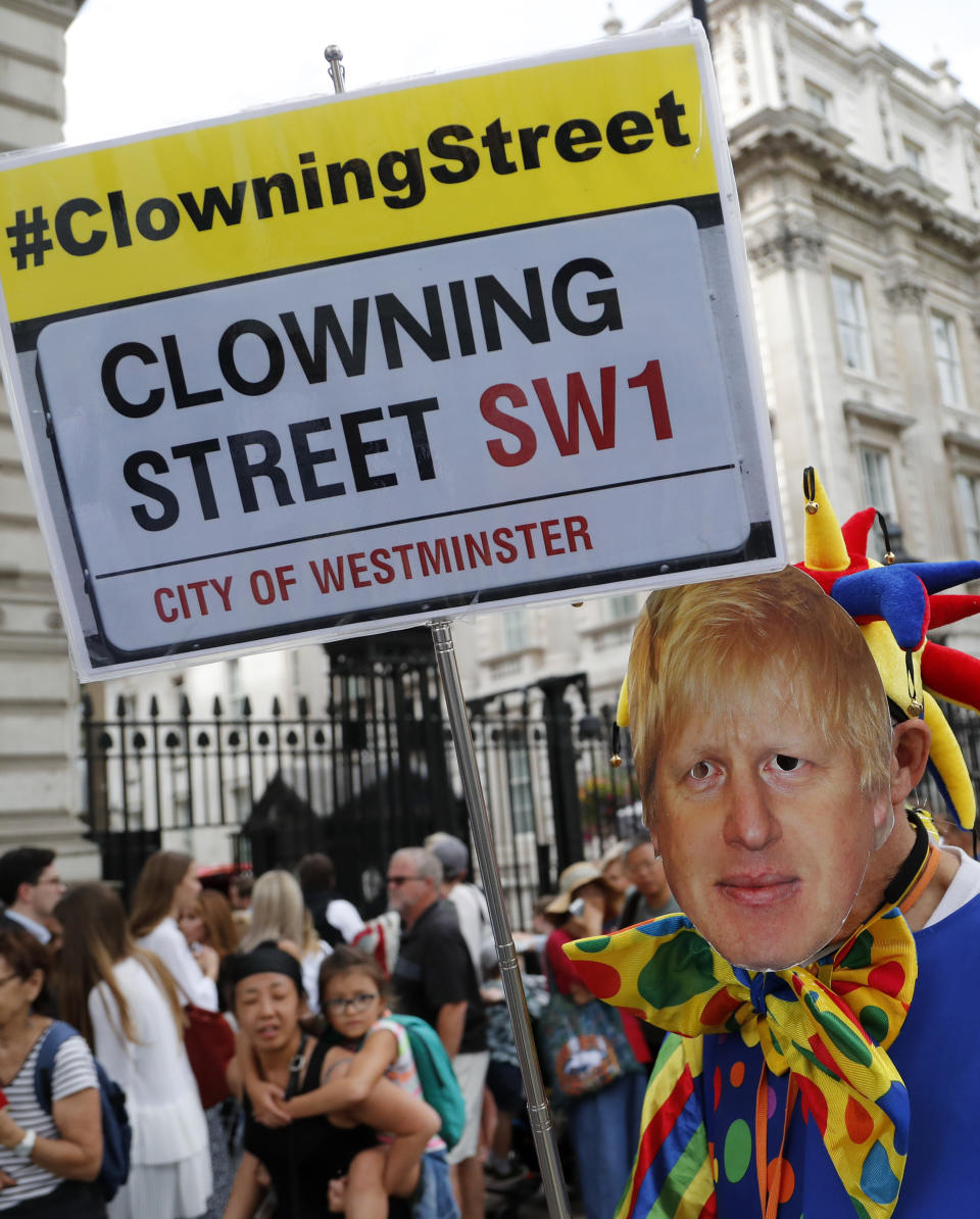 A protestor with a mask of Britain's Prime Minister Boris Johnson demonstrates outside Downing Street in London, Wednesday, Aug. 28, 2019. Prime Minister Johnson has written to fellow lawmakers explaining his decision to ask Queen Elizabeth II to suspend Parliament as part of the government plans before the Brexit split from Europe. (AP Photo/Frank Augstein)