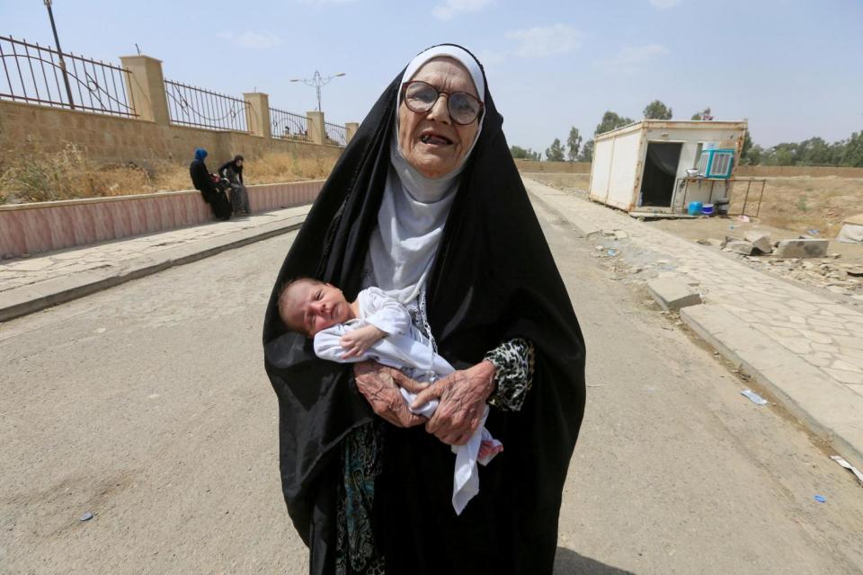 An elderly displaced Iraqi woman who fled from Isis militants carries a baby in Mosul (Reuters)