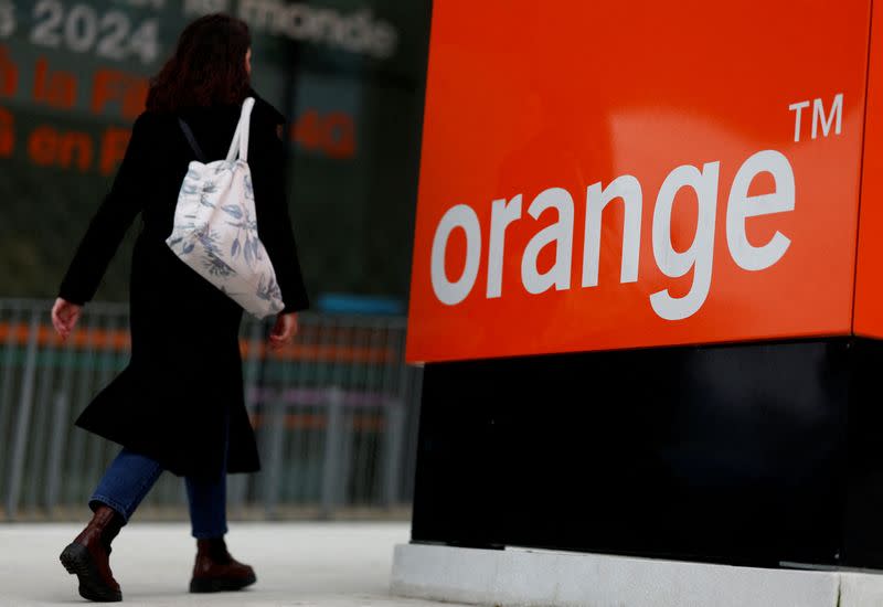 A woman walks past the logo of French telecom operator Orange at the company headquarters in Issy-les-Moulineaux near Paris