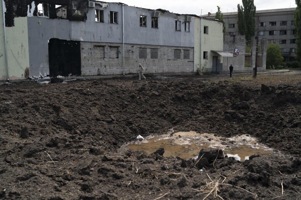People walk past a crater from an explosion that hit an area near the Ukrainian Red Cross Society during a Russian attack yesterday in Sloviansk, Ukraine, Monday, Sept. 5, 2022. (AP Photo/Leo Correa)