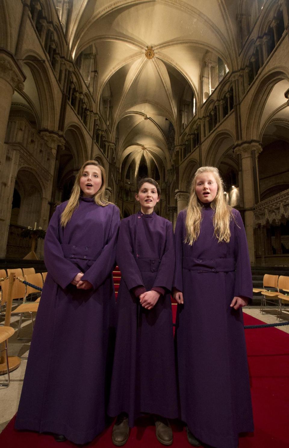 In this Wednesday, Jan. 22, 2014 photo, choristers Poppy Braddy, left, Chloe Chawner, centre, and Abby Cox sing during an interview with the Associated Press in Canterbury Cathedral, Canterbury, England, as the first all female choir at the cathedral rehearses prior to their debut on Jan. 25. The pure, high voices of the choir soar toward the vaulted ceiling of Canterbury Cathedral as they have for more than 1,000 years. Just one thing is different - these young choristers in their purple cassocks are girls, and their public debut at Evensong on Saturday will end centuries of all-male tradition. Canterbury is not the first British cathedral to set up a girls' choir, but as mother church of the 80 million-strong Anglican Communion - one struggling with the role of women in its ranks - its move has special resonance.(AP Photo/Alastair Grant)