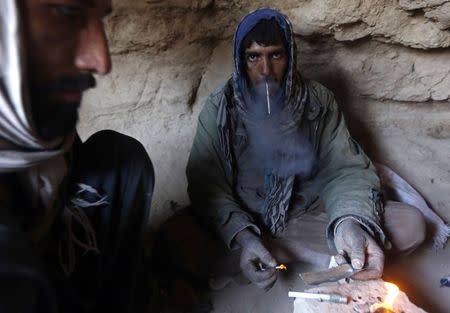 A drug addict smokes heroin inside a cave in Farah province February 4, 2015. REUTERS/Omar Sobhani