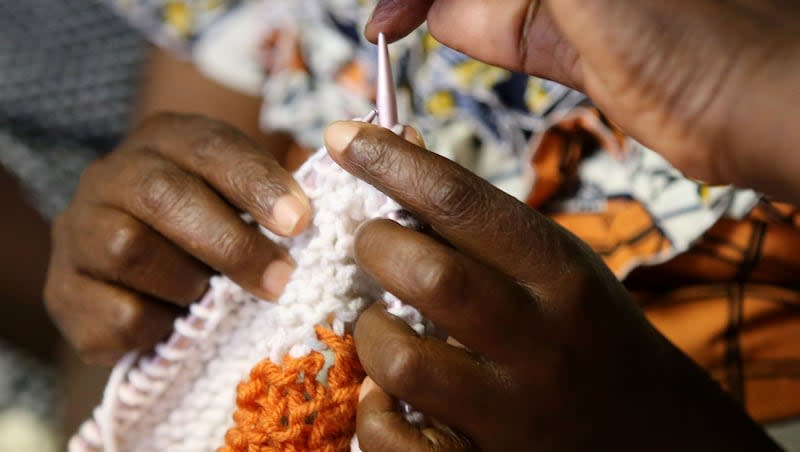 Sifora Bamurange gets some knitting help from Christine Mukankusi at a knitting group meeting for refugee women at the Utah Health and Human Rights office in Salt Lake City, on Tuesday, Oct. 3, 2017.