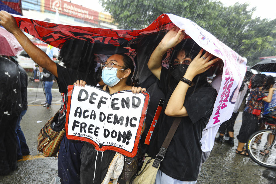 Protesters use banners as rain cover during a suddenn downpour at a rally against the State of the Nation address in Quezon City, Philippines Monday, July 25, 2022. Philippine President Ferdinand Marcos Jr. will deliver his first State of the Nation address Monday with momentum from his landslide election victory, but he's hamstrung by history as an ousted dictator’s son and daunting economic headwinds. (AP Photo/Gerard Carreon)