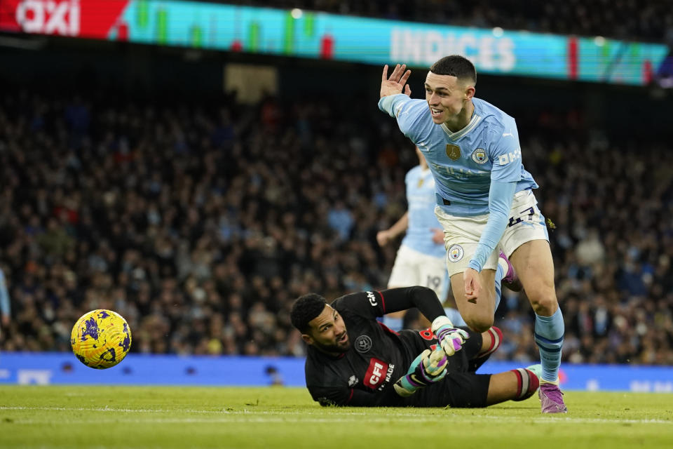 Sheffield United's goalkeeper Wes Foderingham attempts to stop Manchester City's Phil Foden during the English Premier League soccer match between Manchester City and Sheffield United at the Etihad stadium in Manchester, England, Saturday, Dec. 30, 2023. (AP Photo/Dave Thompson)