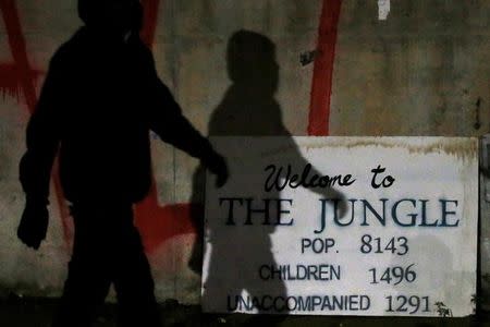 The shadow of a migrant falls on a sign with the population of "The Jungle" at the end of the first day of the evacuation and transfer to reception centers of migrants who were living in tents and makeshift shelters in Calais, France, October 24, 2016. REUTERS/Pascal Rossignol