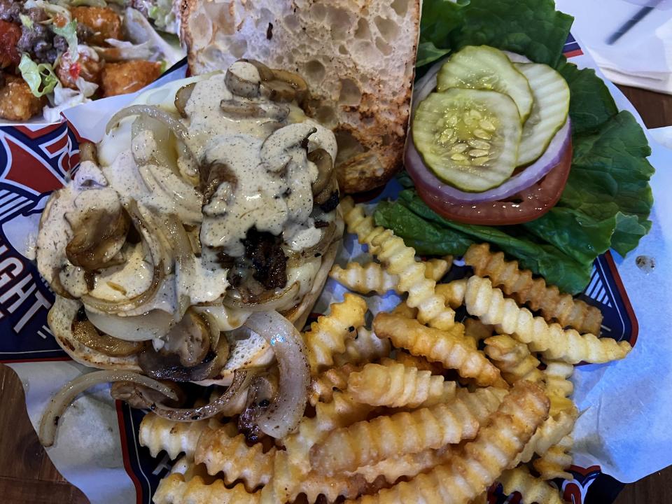 The Ranch Hand burger at Beer Can Alley features grilled mushrooms and onions with crinkle cut fries on the side.