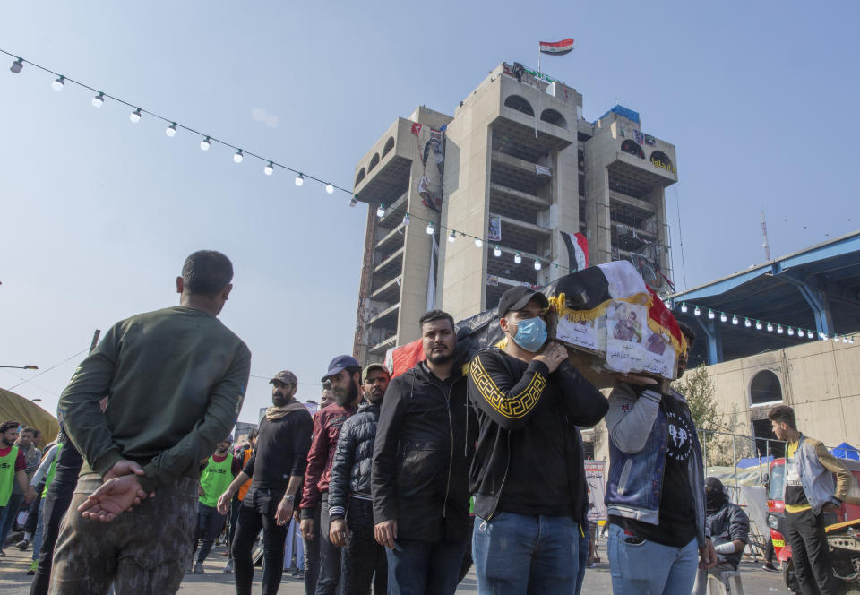 Mourners carry the body of their fellow protester Ameer al-Jalabi, posters with his name and picture on front, during his funeral in Tahrir Square, Baghdad, Iraq, Thursday, Dec. 26, 2019. Ameer succumbed to his wounds on Wednesday after being injured during anti-government demonstrations on October 27, 2019. (AP Photo/Nasser Nasser)