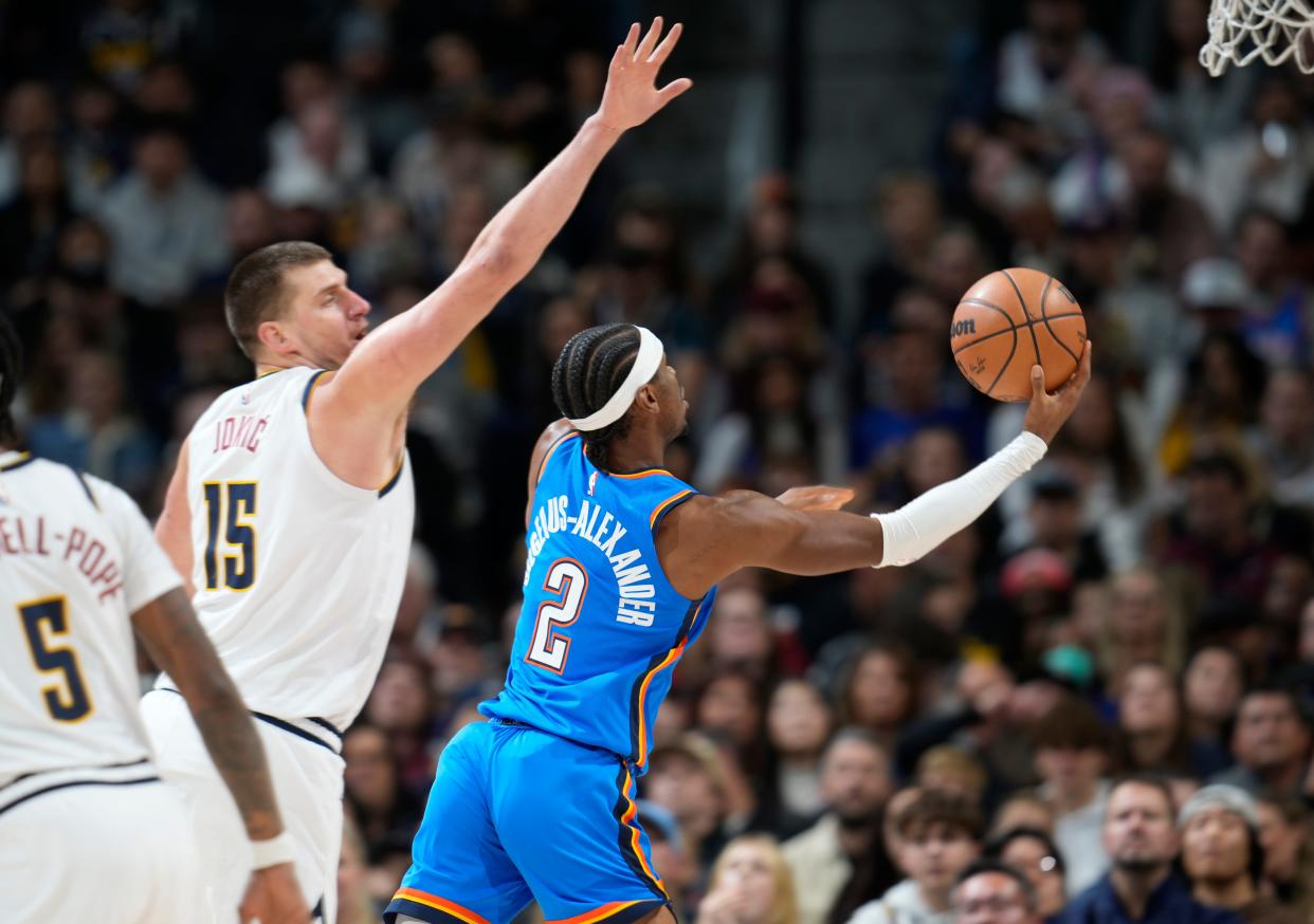 Thunder guard Shai Gilgeous-Alexander, right, gets past Nuggets center Nikola Jokic (15) to the basket in the first half of a game in Denver on Dec. 29, 2023.