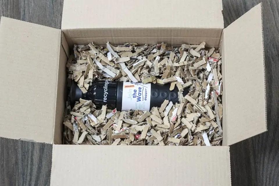 Bottle in a cardboard box with shredded cardboard padding.