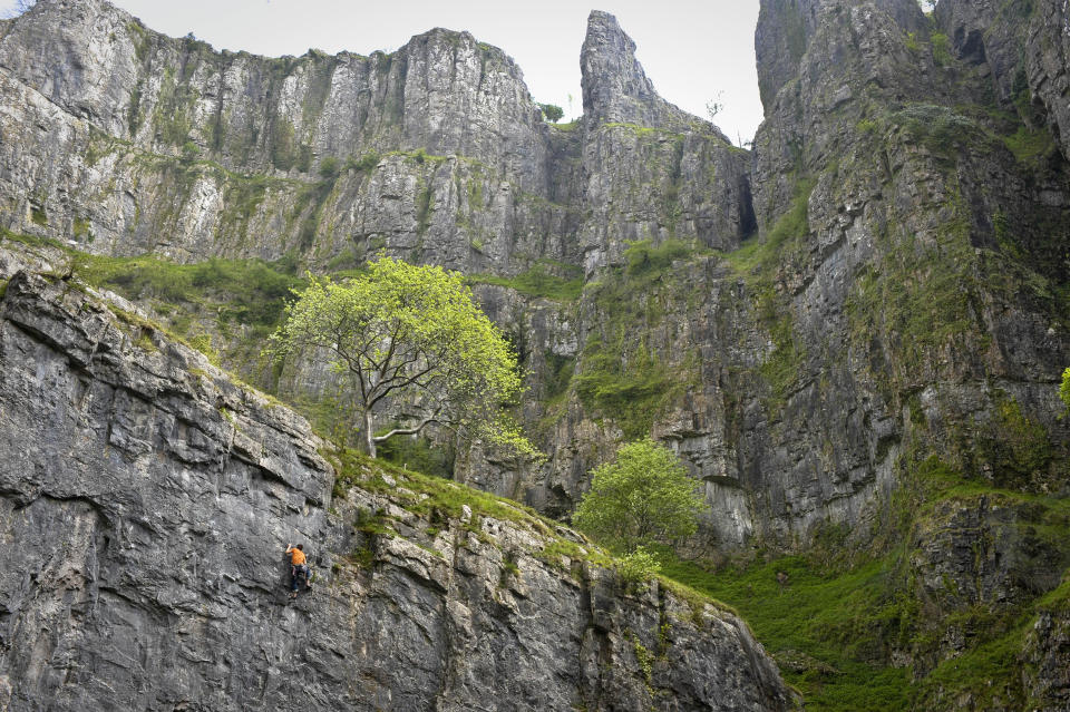 A rock climber dressed in orange reaches for a hand-hold as he attempts the climb at the 'Crag AttaK' event taking place in Cheddar Gorge, Somerset, where rock climbers from all over the word are converging in Britain's Biggest Gorge to take part in the Cheddar Gorge Challenges. 