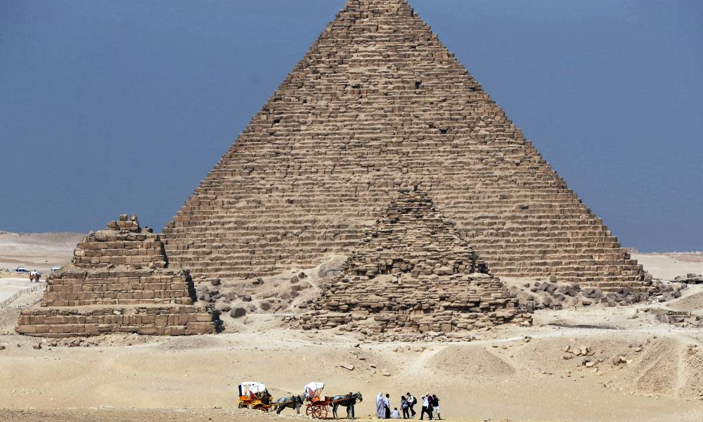 Tourists ride in horse carts near the Giza pyramids, a site where many tourists are targeted by souvenir sellers.