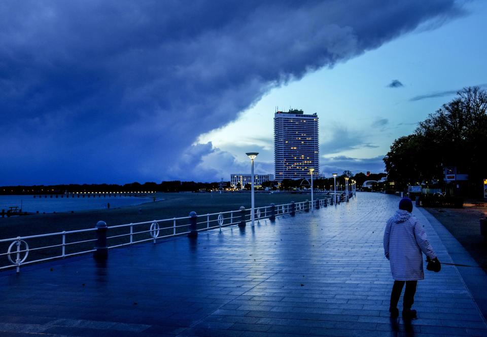 A woman walks on the promenade at the Baltic Sea in Travemuende, northern Germany, Thursday, Oct.21, 2021. Northern Germany was hit by storm and heavy rain falls. (AP Photo/Michael Probst)