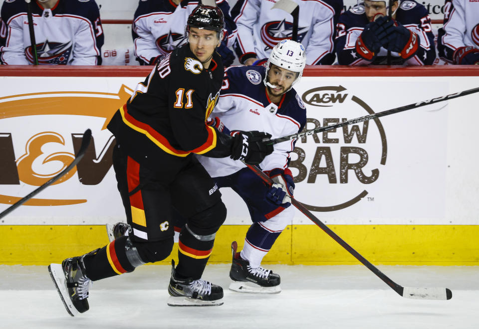 Columbus Blue Jackets forward Johnny Gaudreau, right, is checked by Calgary Flames forward Mikael Backlund during second-period NHL hockey game action in Calgary, Alberta, Monday, Jan. 23, 2023. (Jeff McIntosh/The Canadian Press via AP)