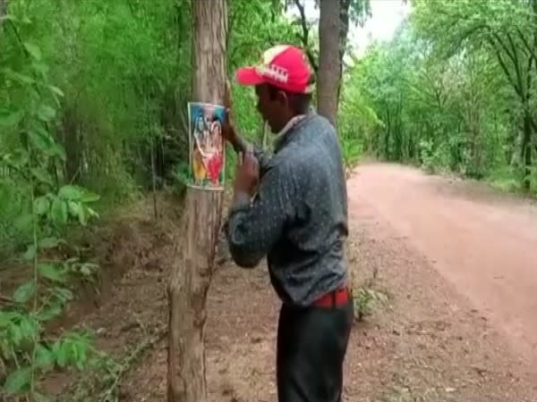 Virendra Singh pasting photo of Gods on trees to save them (Photo/ANI)