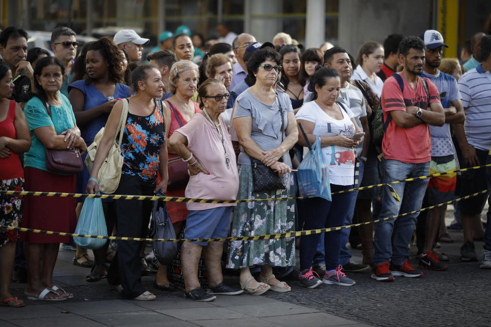 People stand outside the Metropolitan Cathedral in Campinas, Brazil, Tuesday, Dec. 11, 2018. A man opened fire in the cathedral, killing four and leaving four others injured, before taking a bullet in the ribs in a firefight with police and then shooting himself in the head, authorities said. (AP Photo/Victor R. Caivano)