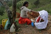 Saturnina Pérez, tía de Yesmin Anayeli, una niña de dos años que murió de neumonía relacionada con desnutrición severa, sostiene la tapa partida del ataúd de su sobrina antes de su entierro en la cima de una colina, en La Palmilla, Guatemala