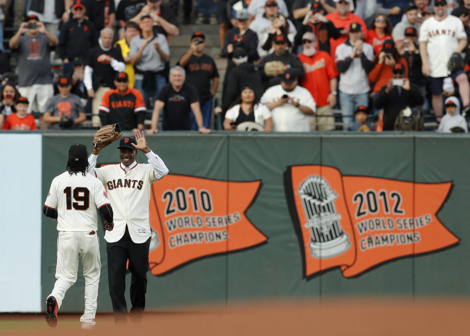 San Francisco Giants' Alen Hanson (19) greets former player Barry Bonds in left field after a ceremony to retire Bonds' jersey number before a baseball game between the Giants and the Pittsburgh Pirates in San Francisco, Saturday, Aug. 11, 2018. (John G. Mabanglo/Pool Photo via AP)