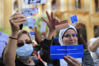 Lebanese depositors show their ATM and Visa cards as they protest outside a bank, in Beirut, Lebanon, Friday, Sept. 24, 2021. Dozens of Lebanese depositors protested throwing eggs and tomatoes on a number of private banks in central Beirut, demanding to have access to their deposits which have been blocked under informal capital controls since the country's financial and economic crisis began in late 2019. (AP Photo/Hussein Malla)