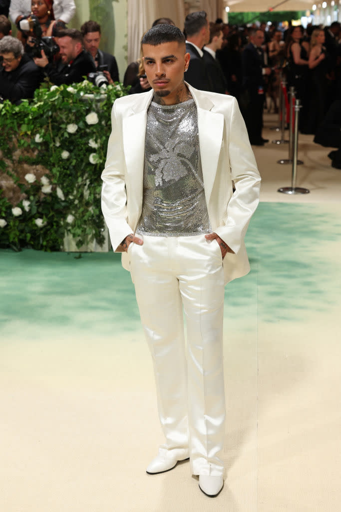 Person in a white suit with a sparkly silver top posing on the Met Gala red carpet